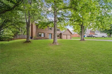 View of front of house featuring a chimney, a garage, central AC unit, brick siding, and driveway