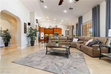 Living room with healthy amount of natural light, arched walkways, recessed lighting, lofted ceiling, and a ceiling fan