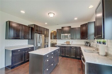 The staggered, dark cabinets are the perfect complement to the white and gray quartz countertops along with the white tile backsplash.