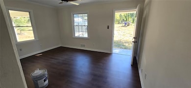 Empty room featuring ornamental molding, ceiling fan, and dark wood-style flooring