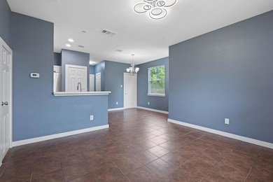 Empty room with a chandelier, dark tile patterned floors, baseboards, a sink, and recessed lighting