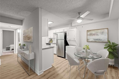 Kitchen featuring white cabinetry, stainless steel appliances, stacked washer and clothes dryer, and a textured ceiling