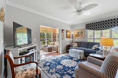 Living area with crown molding, ceiling fan, and wood finished floors