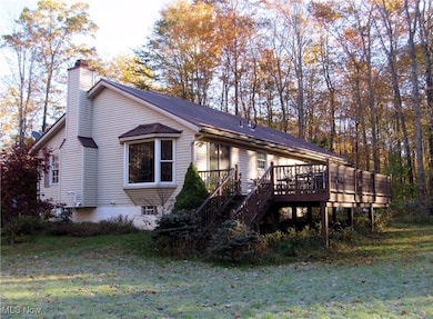 View of front of home with a deck, stairs, a chimney, and a front yard