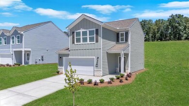View of front of home with board and batten siding, a garage, concrete driveway, a front yard, and roof with shingles