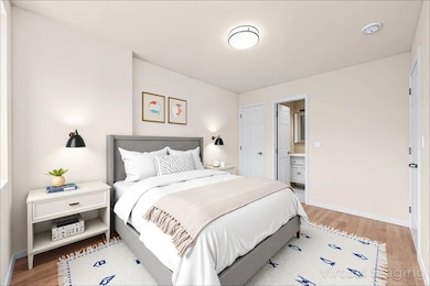 Bedroom featuring light wood-type flooring, baseboards, and ensuite bathroom