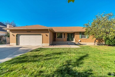 Ranch-style home featuring concrete driveway, brick siding, an attached garage, a porch, and a front yard