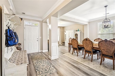 Foyer with light wood-style flooring, a chandelier, and ornamental molding