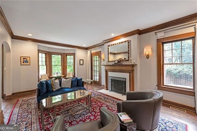 Living area with wood finished floors, ornamental molding, arched walkways, plenty of natural light, and recessed lighting