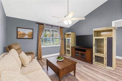 Living area featuring lofted ceiling, light wood finished floors, and a ceiling fan