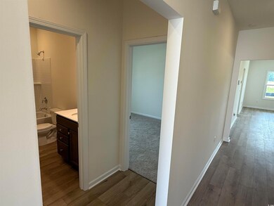 Corridor with dark wood-style flooring and baseboards