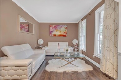 Living room with crown molding, wood finished floors, and baseboards