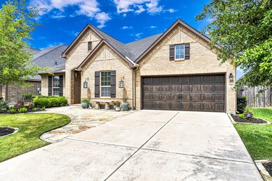 This home features impeccable curb appeal with a masterful design and beautiful brick exterior with a wood finish on the garage door and complementary shutters to match!  Wrought iron lanterns and carriage lights elevate the exterior.  The curved flagstone path, landscaping rocks, and stone bench invite you to the front door.