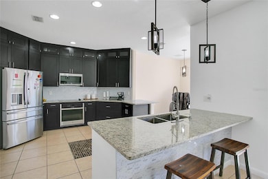 Modern kitchen featuring stainless steel appliances, ample cabinet space, a convenient breakfast bar, and direct access to the dining and living areas.