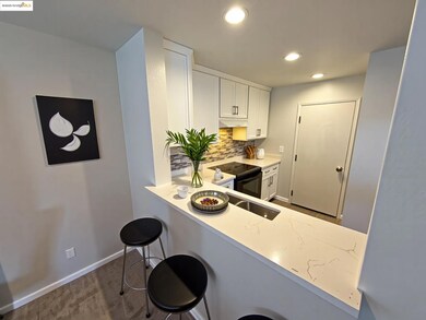 Kitchen featuring white cabinets, a kitchen breakfast bar, decorative backsplash, black electric range, and a peninsula