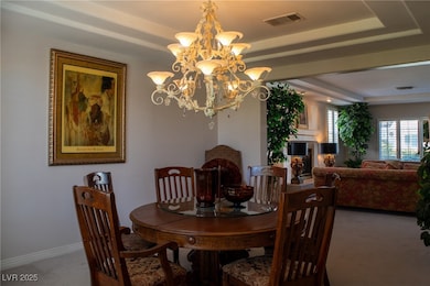 Dining space with carpet, a chandelier, a raised c
