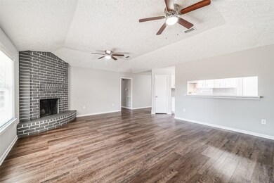 Another view of the large living room area showcasing the many updates such as the ceiling fans, the quartz countertop on the bar and did I mention that wonderful chimney?!