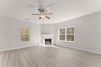 Stock PhotoUnfurnished living room with a premium fireplace, a ceiling fan, light wood finished floors, and baseboards
