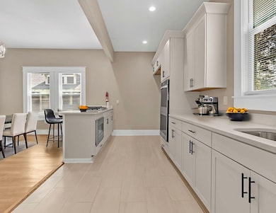 Kitchen featuring healthy amount of natural light, white cabinetry, light countertops, recessed lighting, and a peninsula