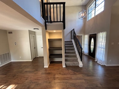 Foyer featuring stairs, dark wood-style flooring, a towering ceiling, and a chandelier