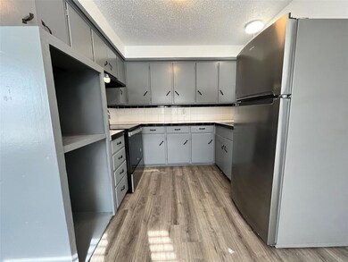This is another view of the kitchen, displaying the giant storage shelf. Notice that the appliances are all brand new.
