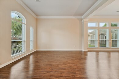 The welcoming den features beautiful floors, custom paint, high ceilings, crown molding, and large windows with privacy blinds!