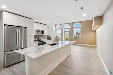 Kitchen with light hardwood / wood-style floors, sink, a kitchen island with sink, and stainless steel appliances
