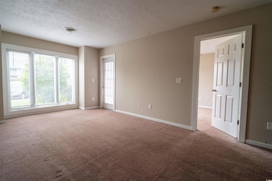 Spare room featuring light carpet, baseboards, and a textured ceiling