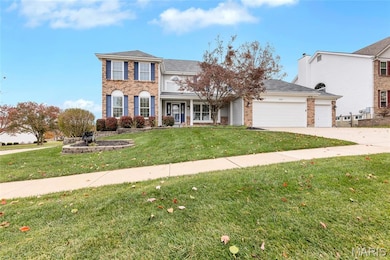 View of front of home featuring a front lawn, brick siding, driveway, garage and covered porch