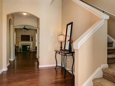 Corridor with arched walkways, wood finished floors, and stairway