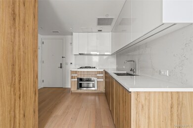 Kitchen with modern cabinets, white cabinetry, decorative backsplash, and appliances with stainless steel finishes