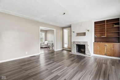 unfurnished living room featuring a textured ceiling, dark wood-style flooring, a fireplace, and built in shelves