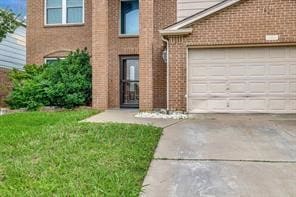 View of front of home with driveway, brick siding, an attached garage, and a front lawn