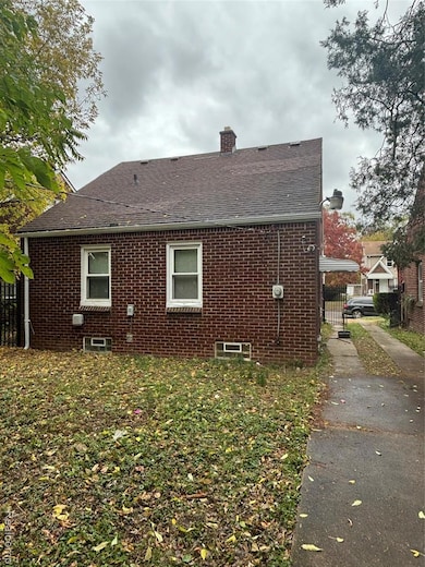 View of side of property with a chimney, brick siding, and roof with shingles
