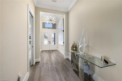 Doorway to outside featuring a notable chandelier, hardwood / wood-style floors, and crown molding