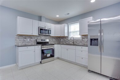 Kitchen with dark stone counters, a sink, backspla