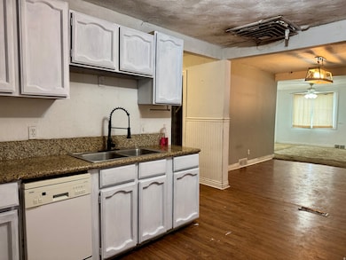 Kitchen with dishwasher, dark wood-style flooring, dark stone countertops, and a ceiling fan