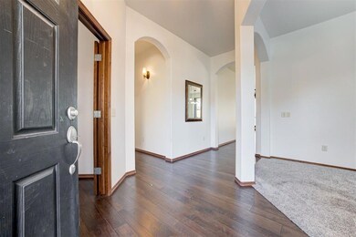 Foyer entrance with dark wood-style floors, arched