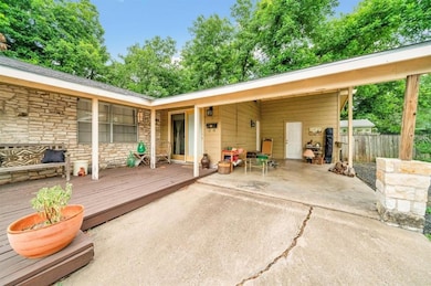 Rear view of house featuring stone siding, a wooden deck, and a patio