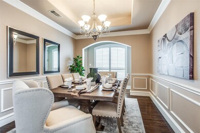 Dining space featuring ornamental molding, a tray ceiling, dark hand-scarped hardwood floors, and an inviting chandelier