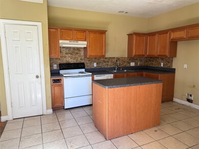 Kitchen features wooden cabinets, a central island