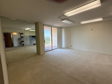 Empty room with expansive windows, a textured ceiling, and carpet flooring