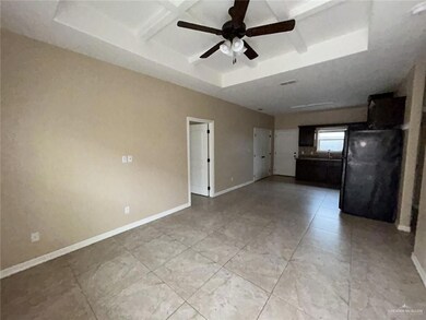 Empty room featuring a ceiling fan, a sink, light tile patterned floors, baseboards, and coffered ceiling