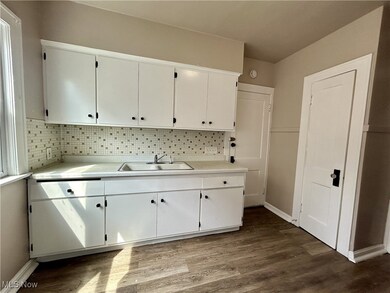 Kitchen with hardwood / wood-style flooring, sink, backsplash, and white cabinetry