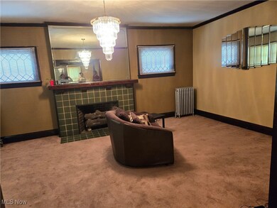 Living area featuring ornamental molding, a fireplace, radiator heating unit, a chandelier, and carpet flooring