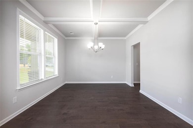 Spare room featuring a chandelier, coffered ceiling, dark wood-type flooring, beam ceiling, and baseboards