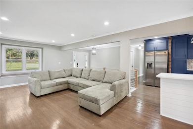 Living room featuring wood-type flooring, ornamental molding, and brick wall