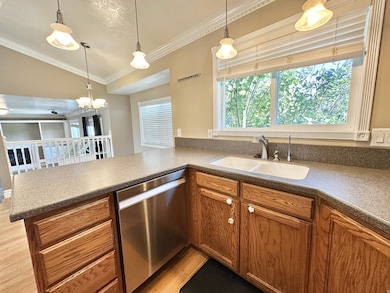 Kitchen featuring dishwasher, lighting, Corian counters, and view of greenery through window