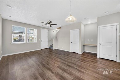 Unfurnished living room with stairs, dark wood finished floors, a textured ceiling, and ceiling fan