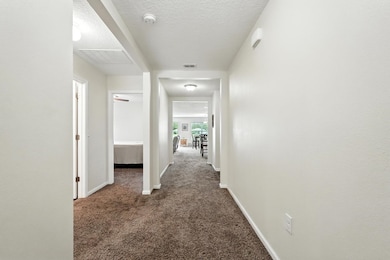 Corridor featuring dark colored carpet and a textured ceiling